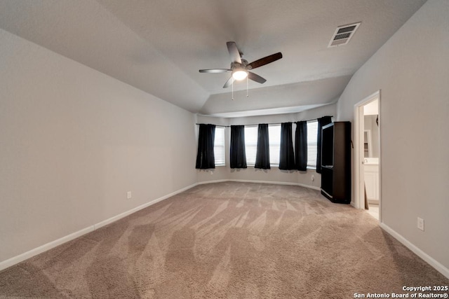 empty room with ceiling fan, lofted ceiling, light colored carpet, visible vents, and baseboards