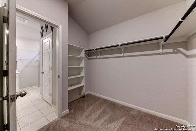 spacious closet with visible vents, vaulted ceiling, and light carpet