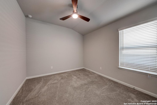 empty room featuring lofted ceiling, ceiling fan, baseboards, and carpet flooring