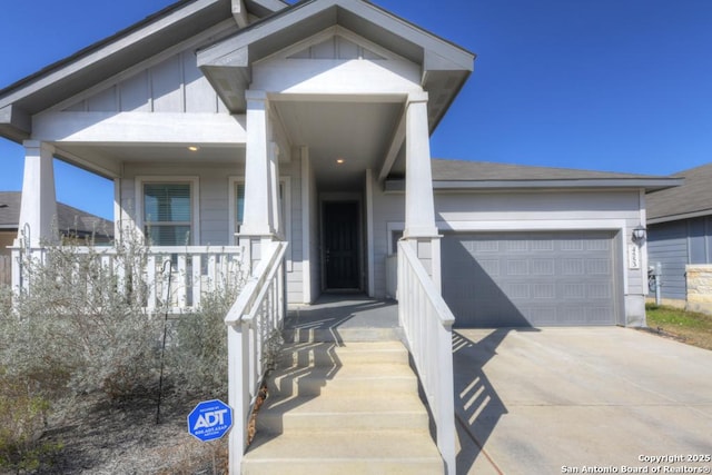 entrance to property with covered porch, concrete driveway, board and batten siding, and a garage