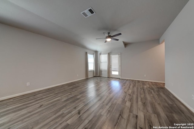 unfurnished room featuring dark wood-style floors, visible vents, baseboards, and a ceiling fan