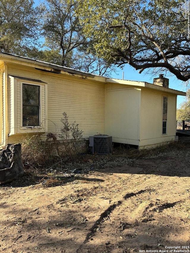 view of property exterior featuring central AC and a chimney