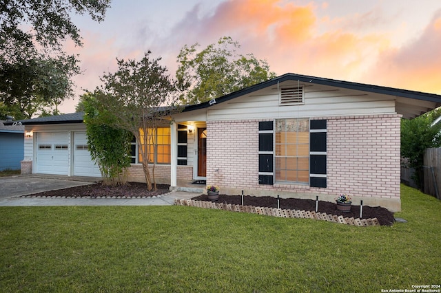 ranch-style home featuring a garage, brick siding, driveway, and a yard