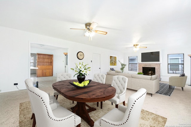 dining room featuring a ceiling fan, carpet, and a brick fireplace