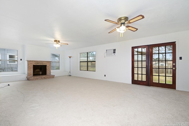 unfurnished living room featuring ceiling fan, an AC wall unit, carpet, and a brick fireplace