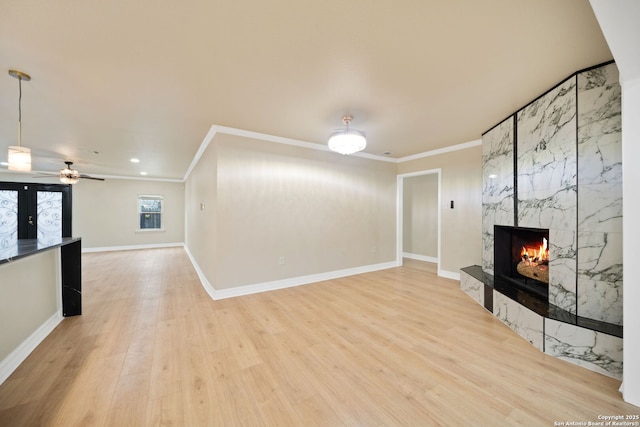 unfurnished living room with ornamental molding, a fireplace, light wood-style flooring, and baseboards