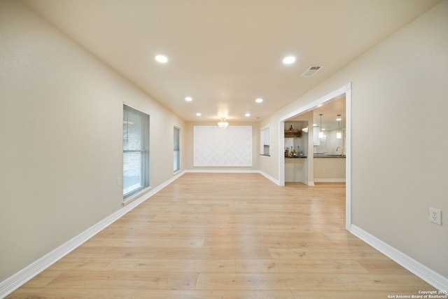 unfurnished living room with light wood-type flooring, visible vents, baseboards, and recessed lighting