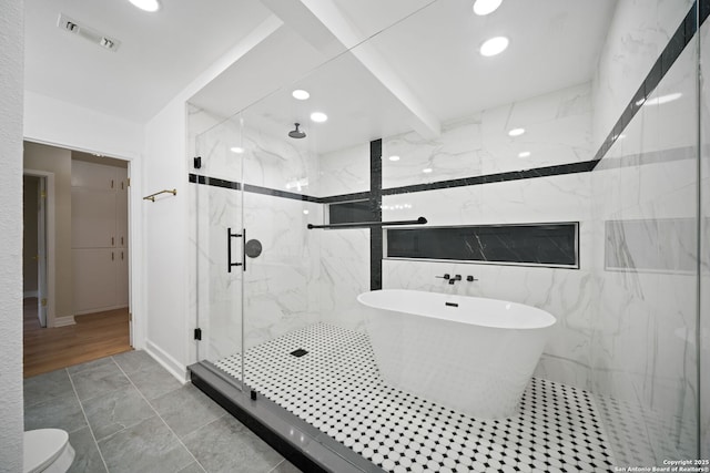 bathroom featuring a marble finish shower, visible vents, a freestanding bath, and recessed lighting