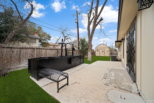 view of yard featuring an outbuilding, a fenced backyard, central AC, a storage unit, and a patio area