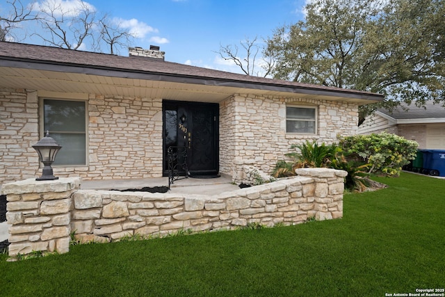 property entrance with stone siding, a chimney, and a yard