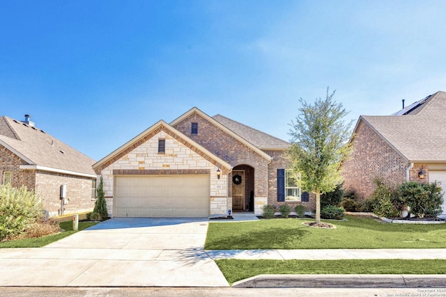 french country style house with brick siding, a garage, stone siding, driveway, and a front lawn