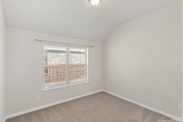 empty room with carpet floors, lofted ceiling, and baseboards