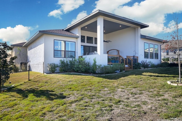 rear view of house with a lawn and stucco siding