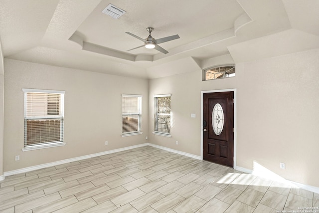 entryway with ceiling fan, visible vents, a raised ceiling, and baseboards