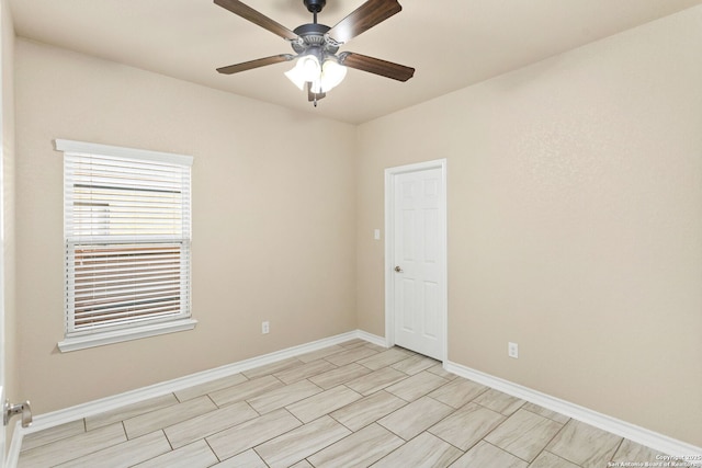 empty room with ceiling fan and baseboards