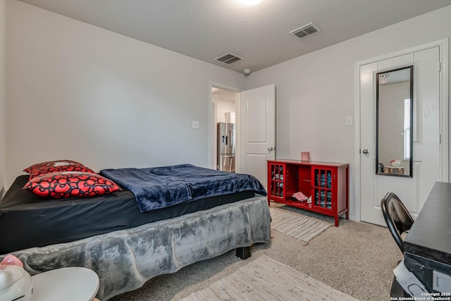 carpeted bedroom with stainless steel fridge and visible vents