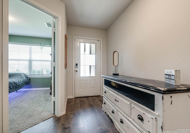 doorway to outside with dark wood-style floors, a wealth of natural light, and baseboards