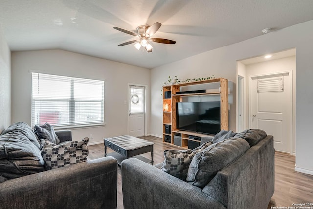 living area featuring vaulted ceiling, ceiling fan, light wood-style flooring, and baseboards