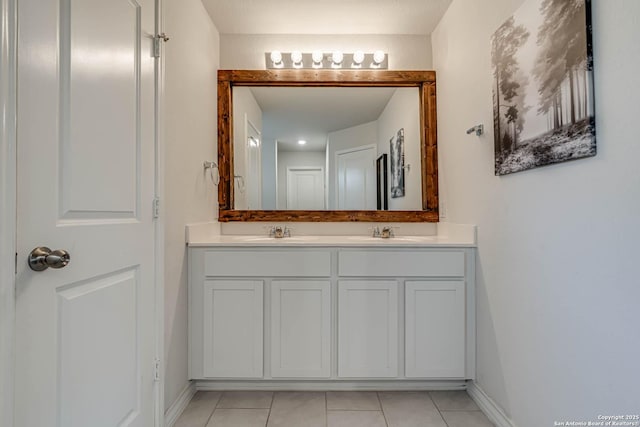 bathroom with double vanity, baseboards, a sink, and tile patterned floors