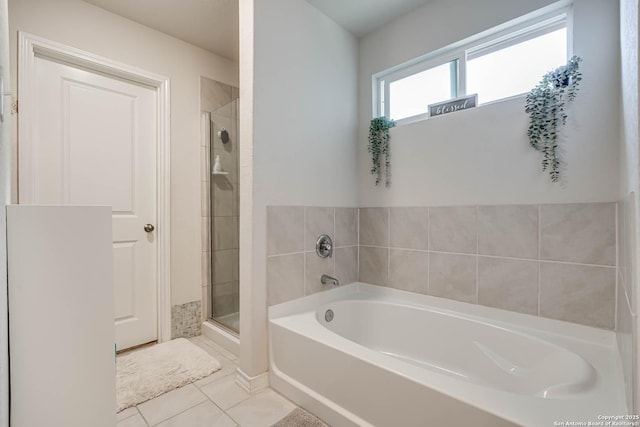 bathroom with a stall shower, a bath, and tile patterned floors