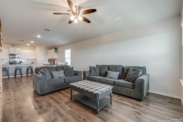 living area with recessed lighting, visible vents, ceiling fan, and wood finished floors