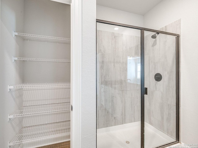 bathroom with a stall shower and a walk in closet