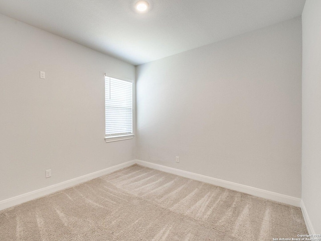 unfurnished room with light carpet and baseboards