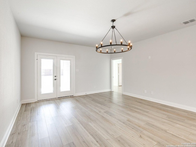 spare room with baseboards, visible vents, french doors, light wood-style floors, and a notable chandelier