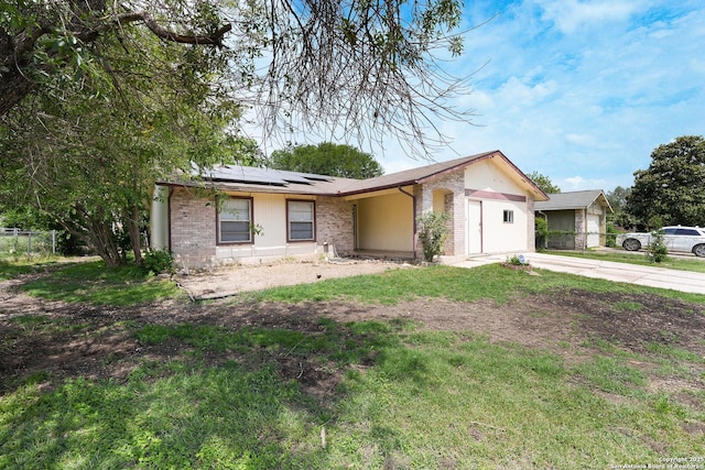 single story home with fence, brick siding, a garage, solar panels, and driveway