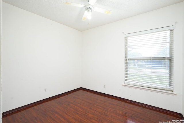 unfurnished room featuring dark wood-style flooring, baseboards, ceiling fan, and a healthy amount of sunlight