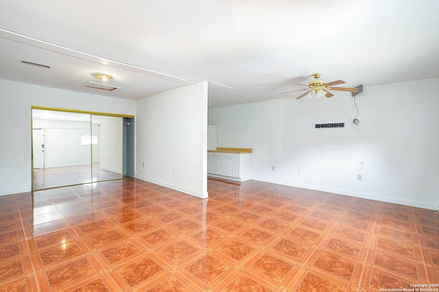 empty room featuring a ceiling fan, baseboards, and visible vents