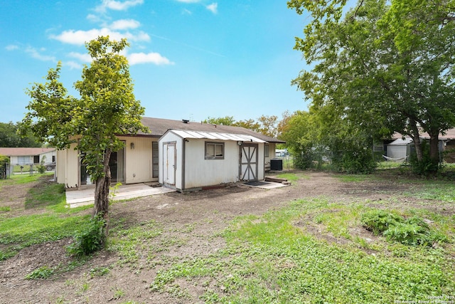 rear view of property with fence, a storage unit, and an outbuilding
