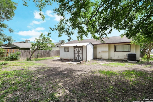 rear view of house with a storage shed, an outbuilding, cooling unit, and a fenced backyard