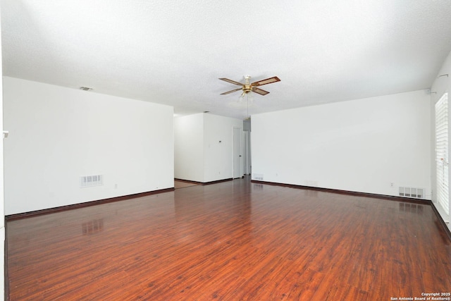 spare room with baseboards, ceiling fan, wood finished floors, and visible vents