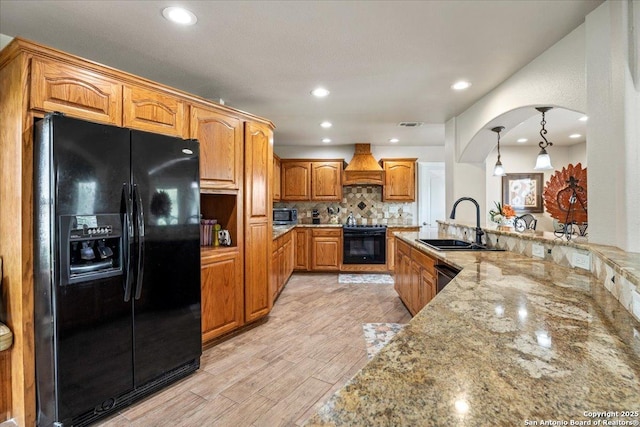 6822 Moss Oak, San Antonio, TX 78229 - kitchen featuring black appliances, a sink, premium range hood, light stone countertops, and brown cabinetry