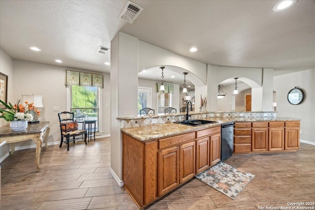 6822 Moss Oak, San Antonio, TX 78229 - kitchen featuring a sink, dishwasher, a textured ceiling, brown cabinets, and light stone countertops
