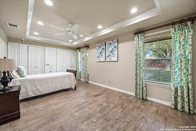 6822 Moss Oak, San Antonio, TX 78229 - bedroom featuring a tray ceiling, baseboards, multiple closets, wood finished floors, and ornamental molding