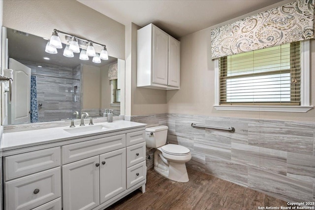 6822 Moss Oak, San Antonio, TX 78229 - bathroom featuring tile walls, toilet, a shower stall, vanity, and wood finished floors