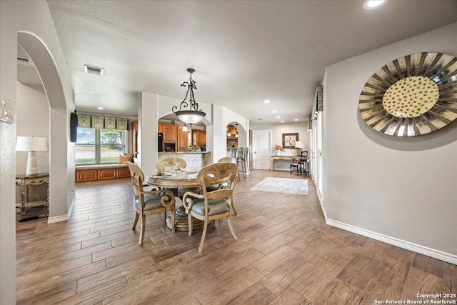 6822 Moss Oak, San Antonio, TX 78229 - dining room with arched walkways, light wood-style flooring, baseboards, and recessed lighting