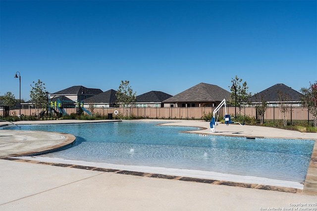 pool with a patio, a playground, and fence