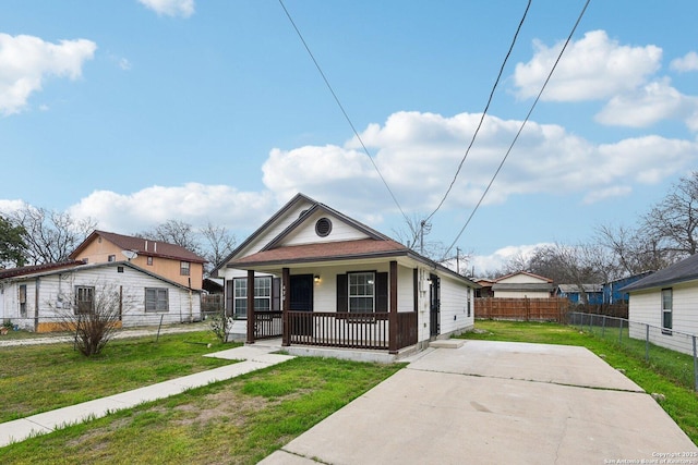 view of front of property featuring covered porch, a front lawn, and fence private yard