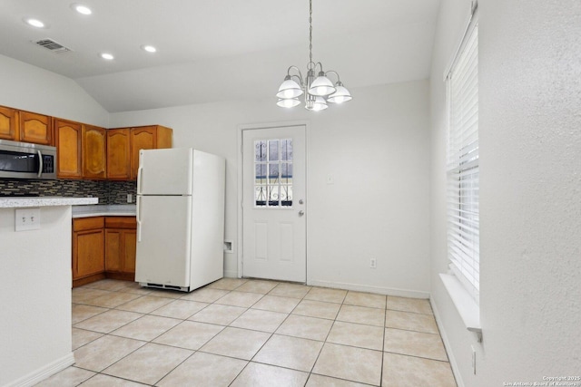 kitchen with visible vents, light countertops, freestanding refrigerator, decorative backsplash, and stainless steel microwave