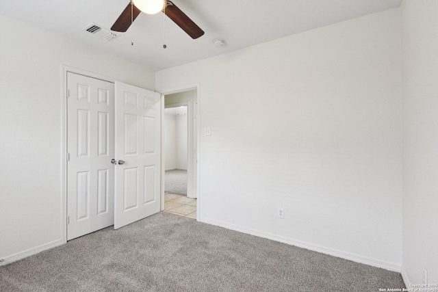 unfurnished bedroom featuring light carpet, a ceiling fan, visible vents, baseboards, and a closet