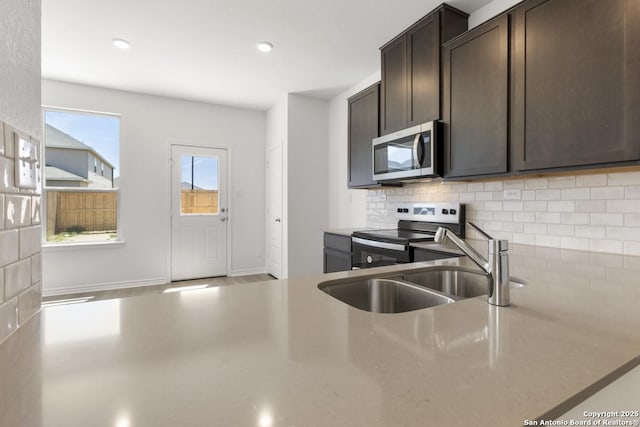 9538 Reinhartz Way, San Antonio, TX 78221 - kitchen with stainless steel appliances, backsplash, dark brown cabinets, a sink, and light countertops