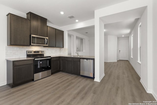9538 Reinhartz Way, San Antonio, TX 78221 - kitchen with appliances with stainless steel finishes, a sink, light wood-style floors, dark brown cabinets, and light countertops