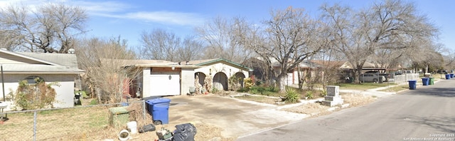 ranch-style home featuring concrete driveway and fence