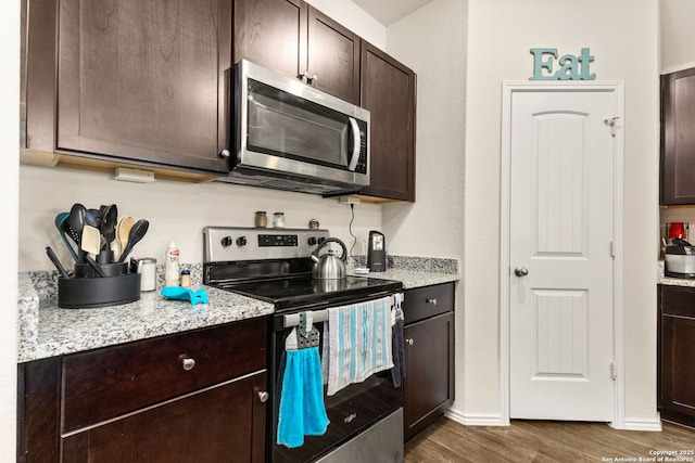 kitchen with stainless steel appliances, dark wood-type flooring, dark brown cabinetry, and baseboards