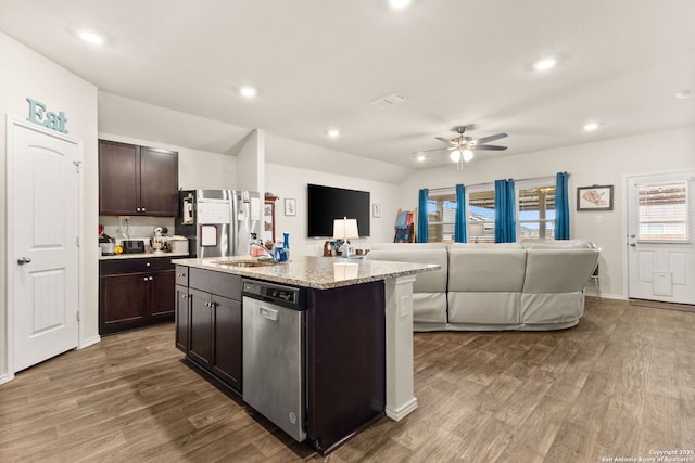 kitchen featuring wood finished floors, a sink, open floor plan, dark brown cabinets, and stainless steel dishwasher