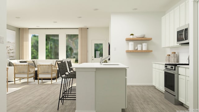 kitchen with a kitchen island with sink, a sink, light wood-style flooring, and stainless steel electric stove