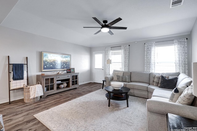 living room with a ceiling fan, baseboards, visible vents, and wood finished floors